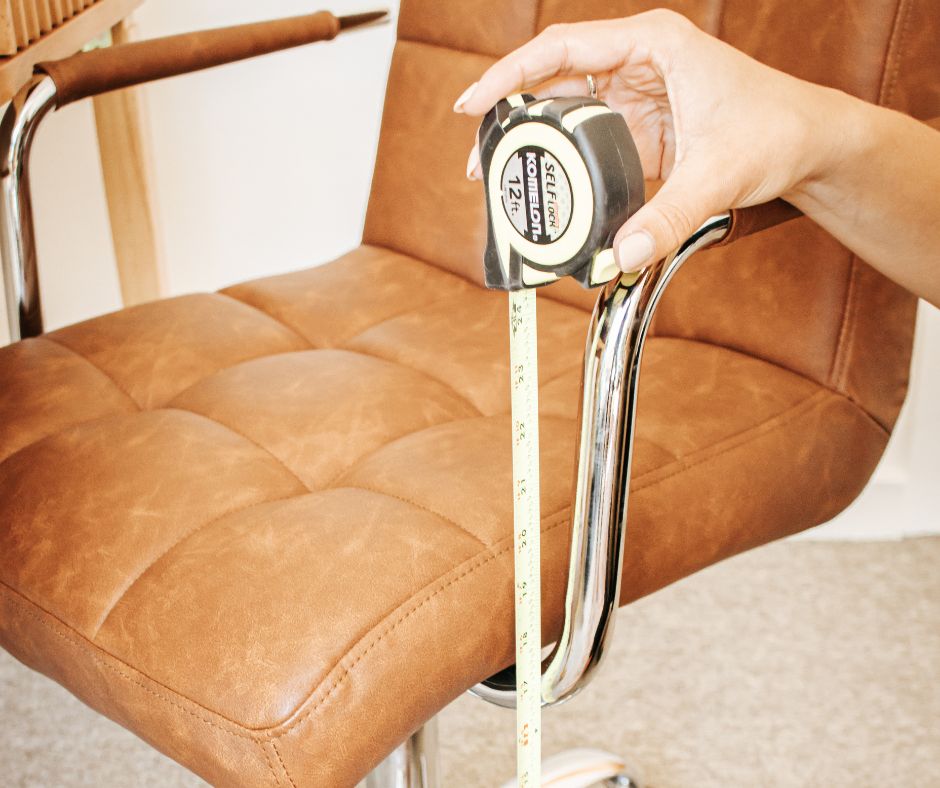 Person measuring a brown leather chair with a tape measure during ergonomic assessment consultation