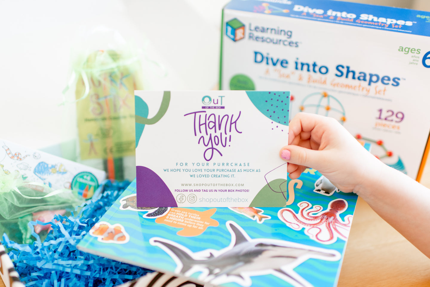 OuT of the Box educational activity set with a 'Thank You' card and child's hand holding it.