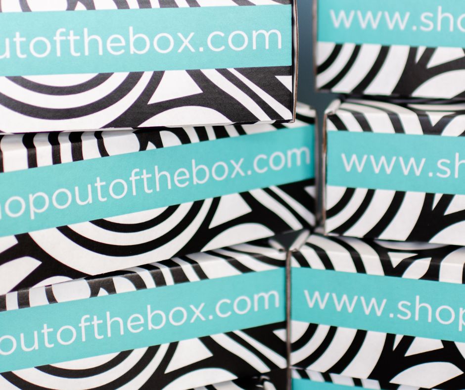 Stack of occupational therapy boxes with 'shopoutofthebox.com' branding on a black and white patterned background.
