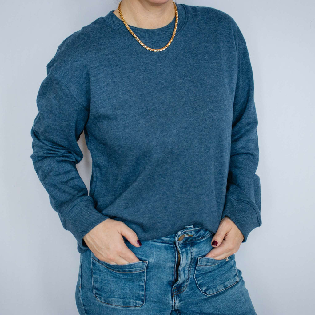 Person wearing a blue Excel Therapy Services sweatshirt and jeans against a white background